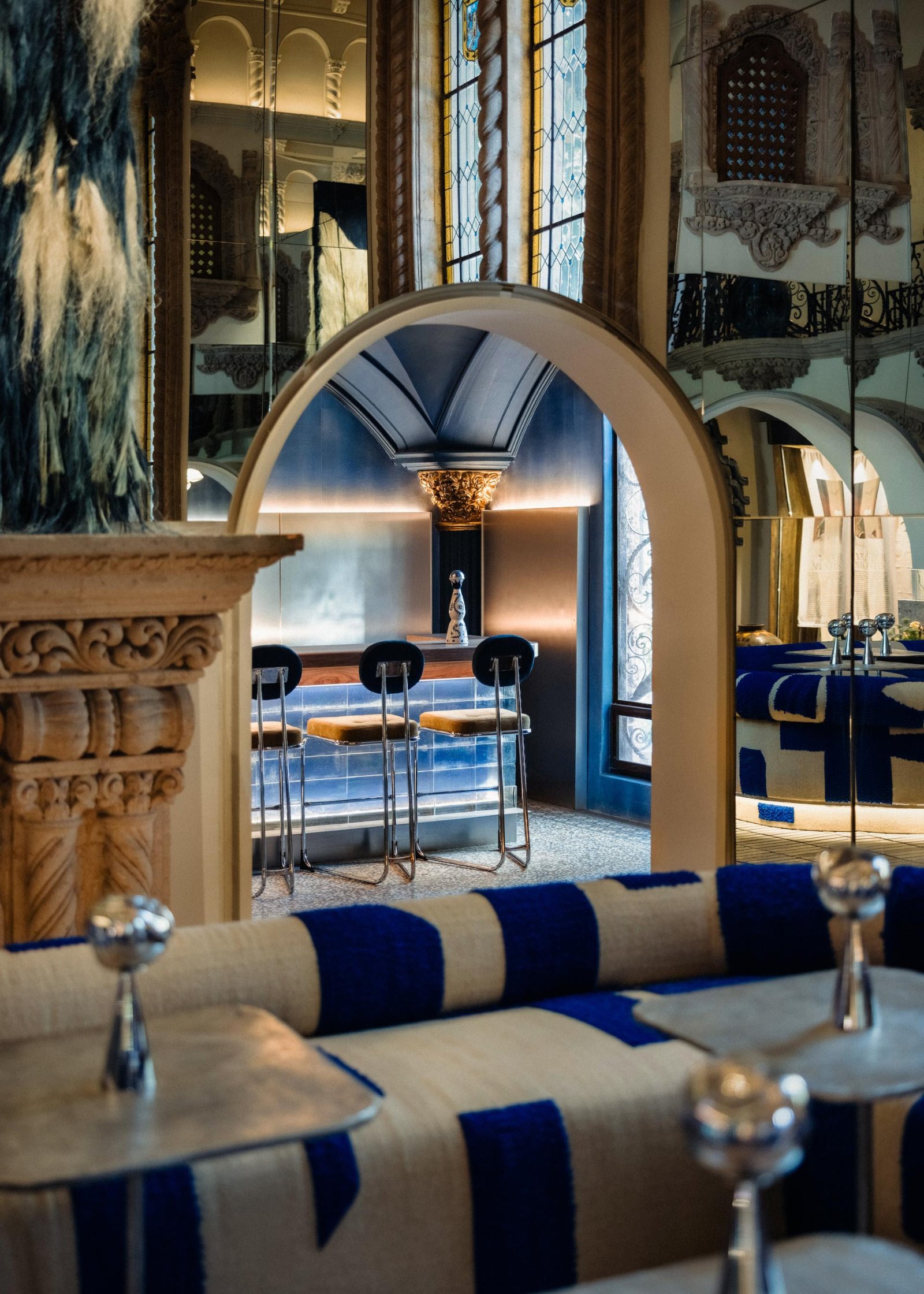 Salon avec banquettes rayées bleu et blanc sous de hauts plafonds