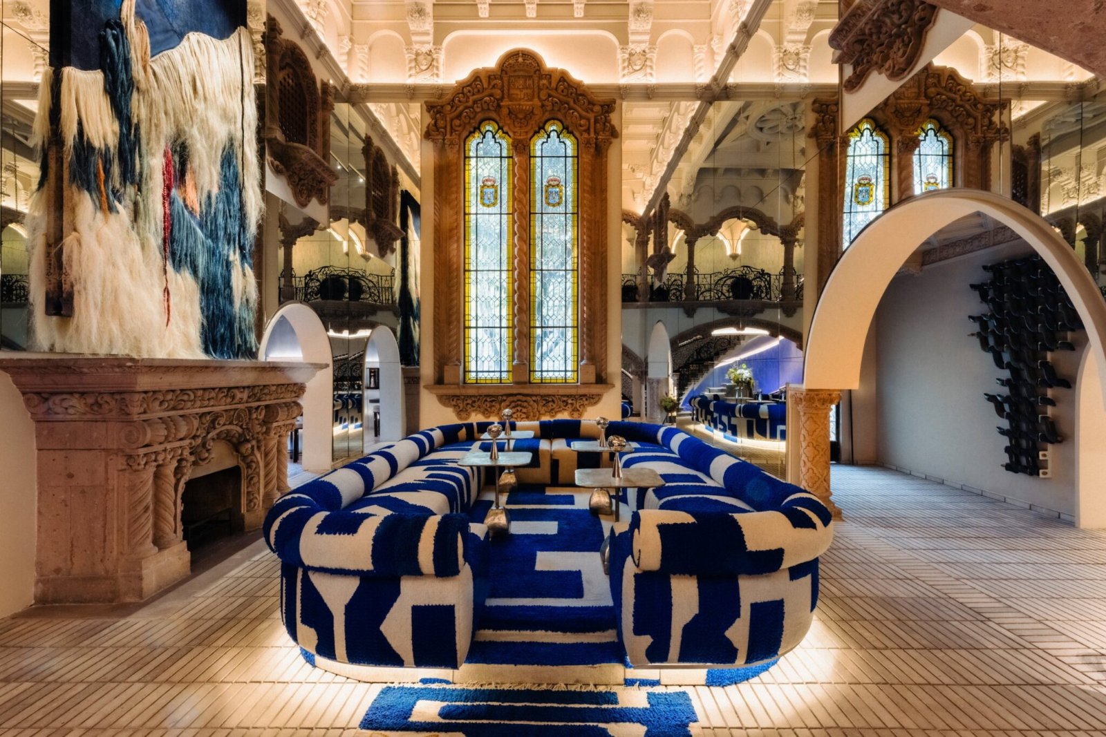 Salon de la Casa de Los Leones avec canapé bleu et blanc, vitraux et cheminée sculptée