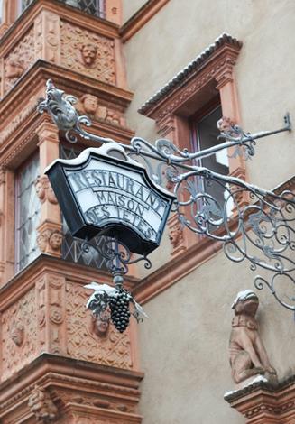 Enseigne en fer forgé et têtes sculptées de La Maison des Têtes à Colmar