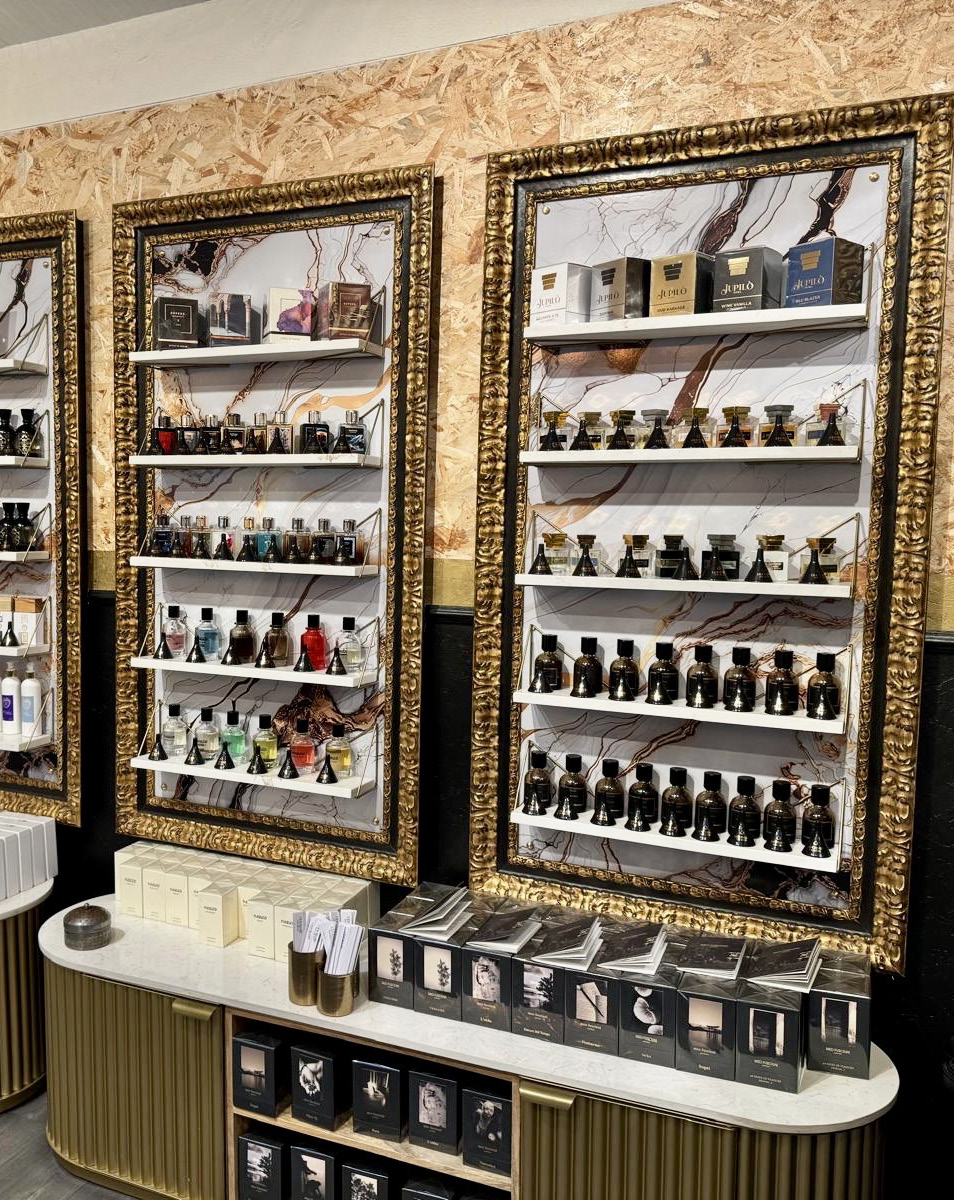 Vitrine murale encadrée de dorures présentant des parfums chez Odorare